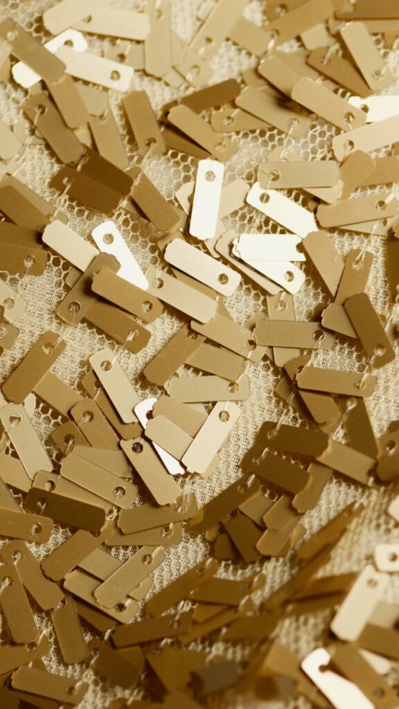 The Art of Drawing Readers In: Your attractive post title goes here A vertical close-up of golden rectangular sequins scattered on decorative lace fabric.